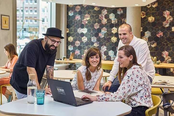 Beehive will im Zuge der Kooperation Geschäftsreisende in seine Co-Working-Spaces locken. © Beehive GmbH Leute versammeln sich an einem Arbeitstisch