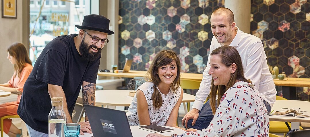 Beehive will im Zuge der Kooperation Geschäftsreisende in seine Co-Working-Spaces locken. © Beehive GmbH Leute versammeln sich an einem Arbeitstisch